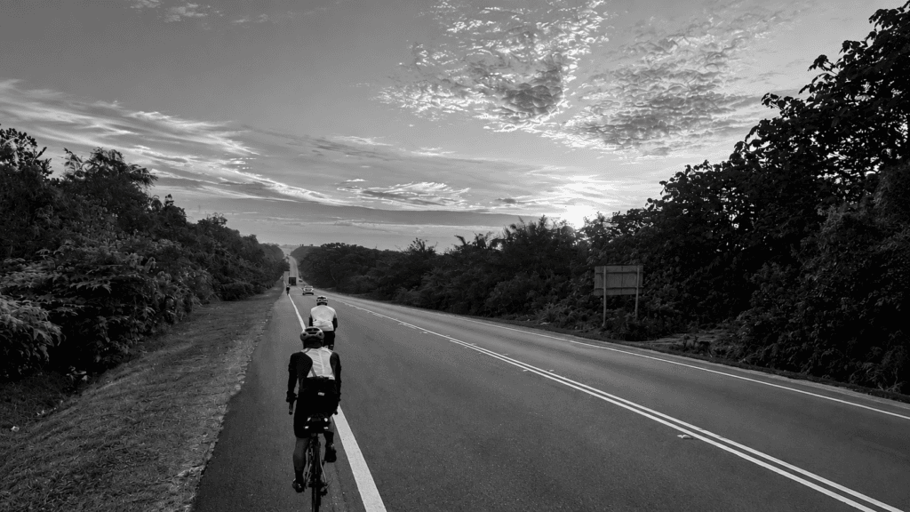 Randonneurs riding along a road at dawn in black and white